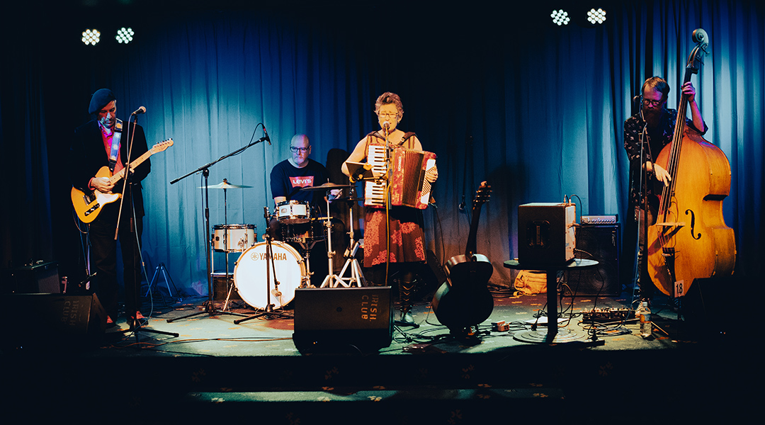 Queen Juanita sings and plays piano accordion on stage at the Irish Club
